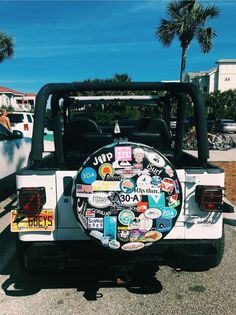 a white jeep with stickers on it parked in a parking lot next to palm trees