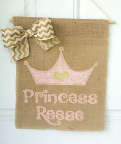 a burlap banner with a pink princess's crown on it hanging from a door