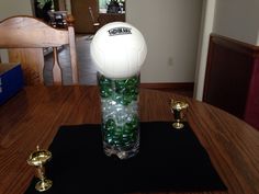 there is a volleyball in a vase filled with water and green balls on the table