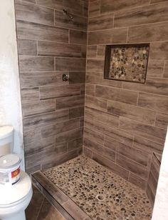 a white toilet sitting next to a walk in shower under a tiled wall and floor