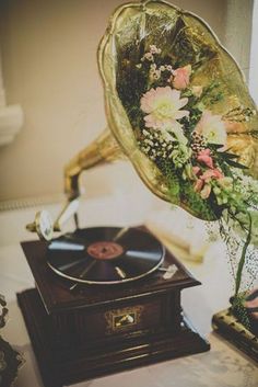 an old record player with flowers on it sitting next to a vase filled with flowers