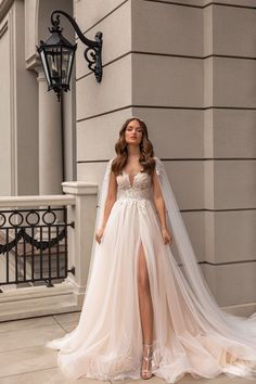 a woman wearing a wedding dress and veil standing on the sidewalk in front of a building