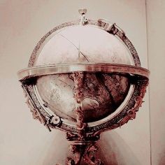 an antique looking globe is on display in a room with white walls and flooring