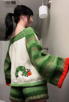 a woman in green and white sweater standing next to a toilet