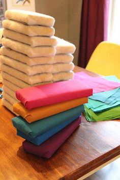 a stack of folded towels sitting on top of a wooden table next to a yellow chair