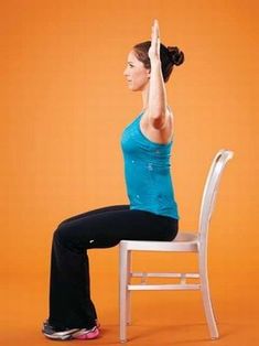 a woman sitting on top of a white chair with her hands up in the air