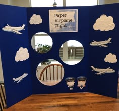 a paper airplane flight display with cutouts on the front and back sides, sitting on top of a wooden table