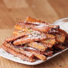 a white plate topped with cooked carrots on top of a wooden table