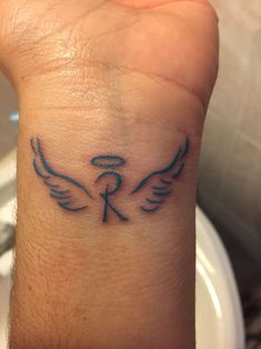 a small tattoo on the wrist of a person's left hand, with two wings