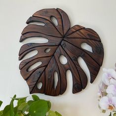 a large wooden leaf shaped wall hanging next to a potted plant