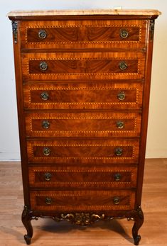 an antique chest of drawers with marble top and brass hardware on the bottom, sitting on a hard wood floor