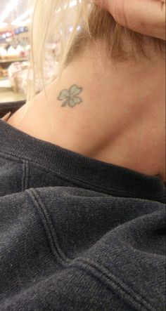 a woman with a four leaf clover tattoo on her neck