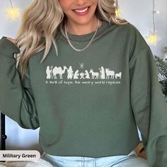 Celebrate the true meaning of Christmas with this beautifully embroidered Christian Christmas sweatshirt, perfect for the holiday season. Featuring a minimalist nativity scene silhouette and the powerful lyrics, "With a thrill of hope, the weary world rejoices," this soft and cozy green sweatshirt captures the essence of hope and joy found in the birth of Christ. Ideal for church gatherings, family celebrations, or simply spreading the message of peace, this Christmas sweatshirt is a meaningful Nativity Scene Silhouette, Christmas Sweatshirt Ideas, Faith Clothing, Green Sweatshirt, True Meaning Of Christmas, Religious Christmas, Christian Christmas, Family Celebrations, Fitted Sweater