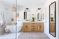 a bathroom with two sinks, mirrors and a bathtub in the middle of it