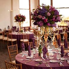 the centerpieces on this table are adorned with purple flowers