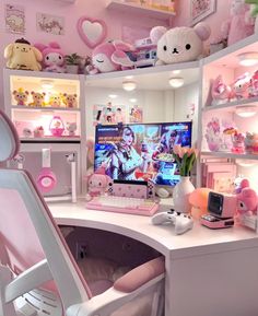 a white desk topped with a computer monitor next to a chair and shelves filled with stuffed animals