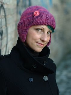 a woman wearing a pink knitted hat next to a wall