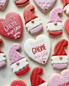 there are many decorated cookies on the table with pink and red frosted hearts, hats, and other decorations