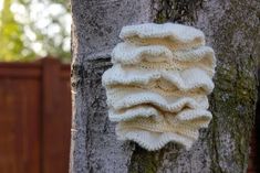 a crocheted sweater hanging on the side of a tree