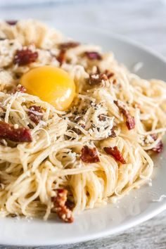 a white plate topped with pasta and an egg