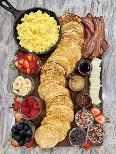 a breakfast platter with pancakes, fruit, eggs, bacon, and other foods