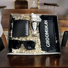 an open box containing sunglasses, flasks and other personal items on a table