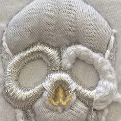 two pieces of silver and gold wire on top of a white pillow with an odd design