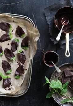 there are chocolates on the table with spoons next to it and two bowls full of them