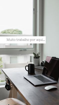 an open laptop computer sitting on top of a wooden desk next to a coffee cup