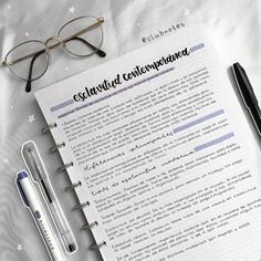 a notepad and pen sitting on top of a bed next to a pair of glasses