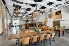 a large room with tables, chairs and plants hanging from the ceiling in front of them