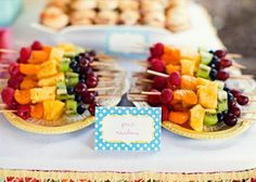 a table topped with lots of fruit on top of a white table covered in food