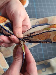 a person is tying a ribbon on a piece of fabric with scissors in their hands