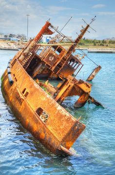 an old rusted ship sitting in the middle of the ocean with water around it