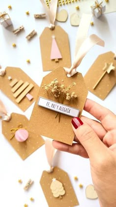 a hand holding a piece of paper with gold decorations on it and some tags attached to it