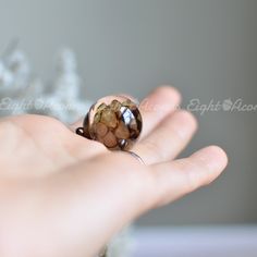 a woman's hand is holding a ring with flowers on the inside of it