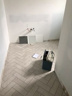 an empty room with white walls and grey flooring is shown in the foreground