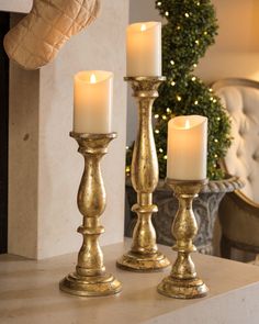 three candles sitting on top of a table next to a christmas tree