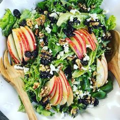 a salad with apples, blueberries and walnuts in it on a white plate