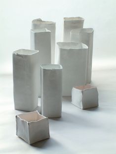 several white vases sitting on top of each other in front of a white background