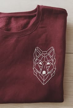 a red t - shirt with a white geometric fox on it's left chest