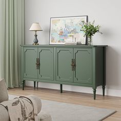 a living room with a green cabinet next to a lamp and a painting on the wall