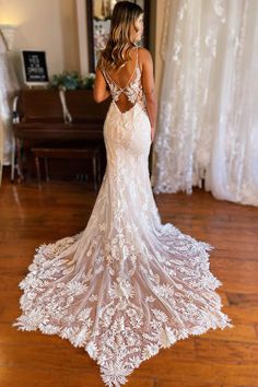 a woman in a white wedding dress standing on a wooden floor with her back to the camera