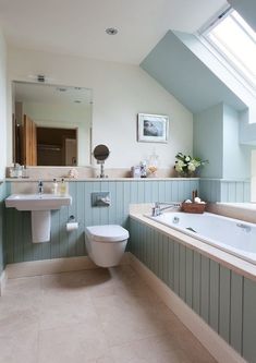 a bathroom with a skylight above the toilet and bathtub, along with two sinks