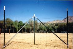 a wire fence in an open field with mountains in the background