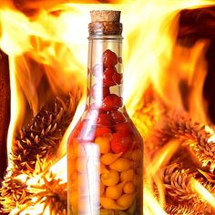 a glass bottle filled with jelly beans sitting on top of a table next to fire