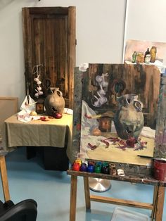 an artist's studio with paintings on easels and other art work in the background