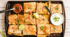 mexican food on a tray with dipping sauce