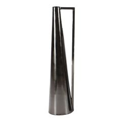 a tall metal vase sitting on top of a table