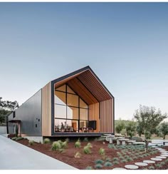 a modern house with wooden slats on the roof and side walls, along with an outdoor dining area